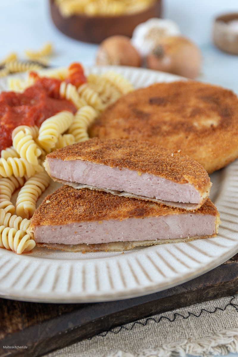 Panierte Jagdwurst mit Tomatensoße und Spirelli.
