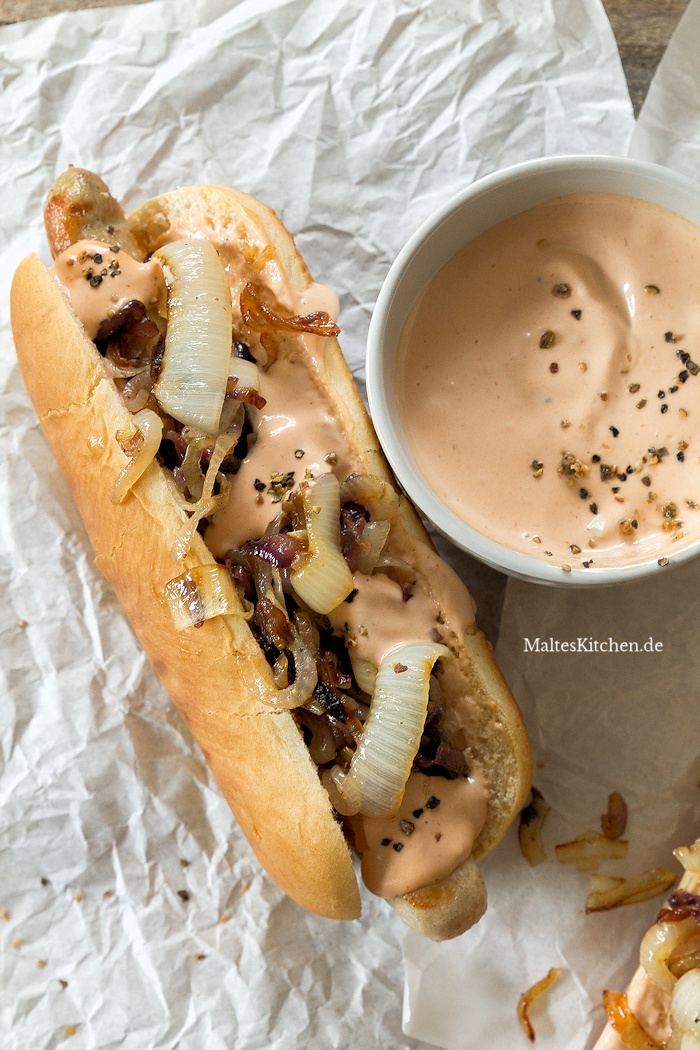Hot Dog mit Sauce, Bratwurst und gegrillten Zwiebeln
