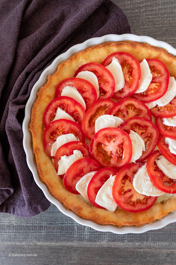Der Boden wird mit Tomaten und Mozzarella belegt