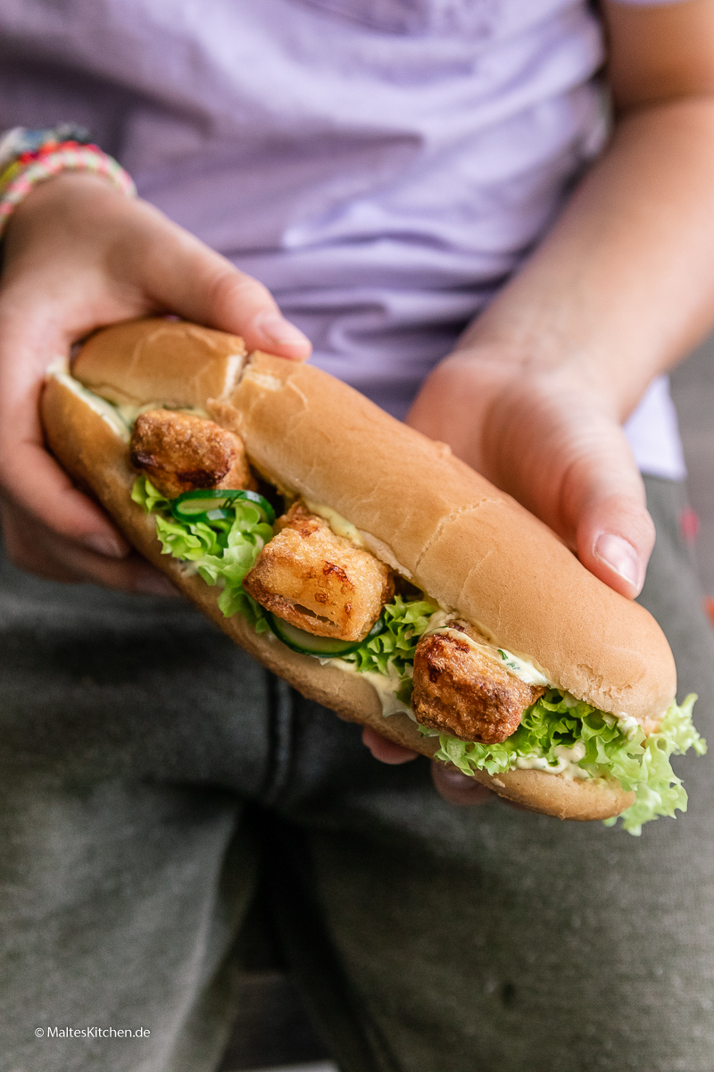 Knusprige Fischstäbchen im Hot Dog mit Gurken und Salat.