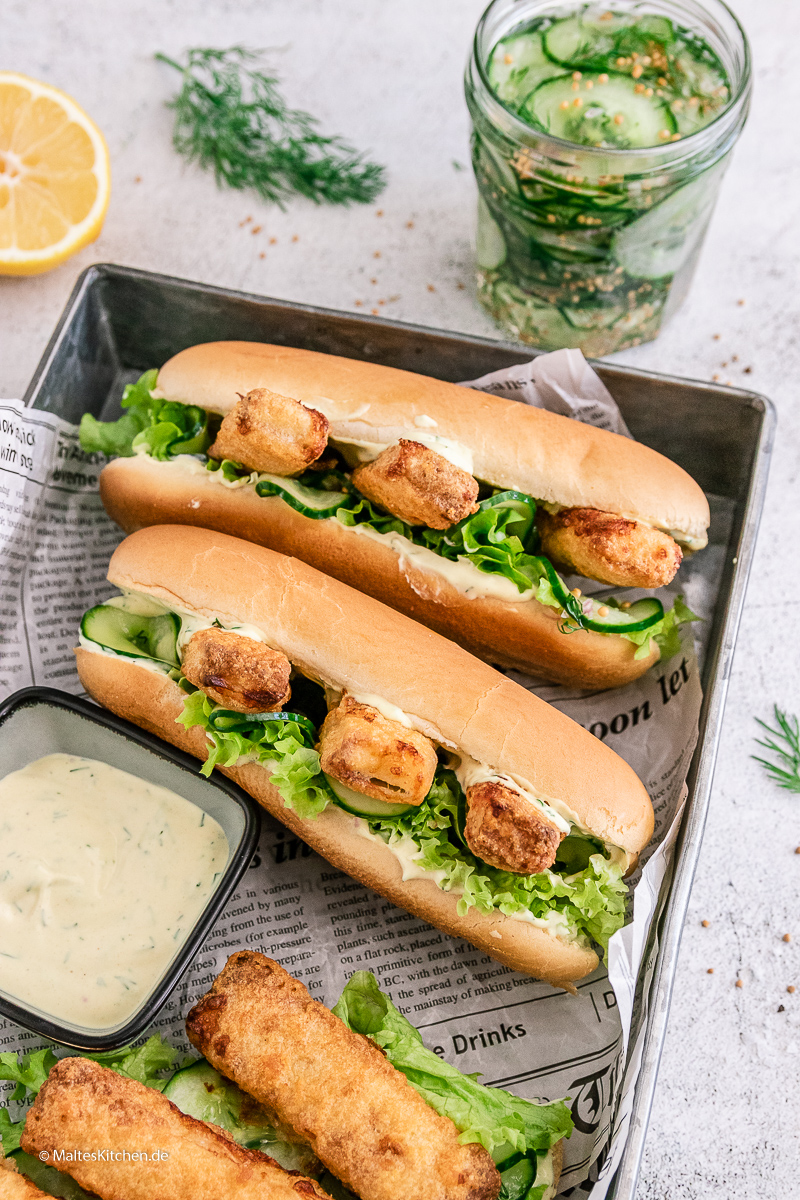 Hot Dog mit Fischstäbchen, Gurken und Sauce.
