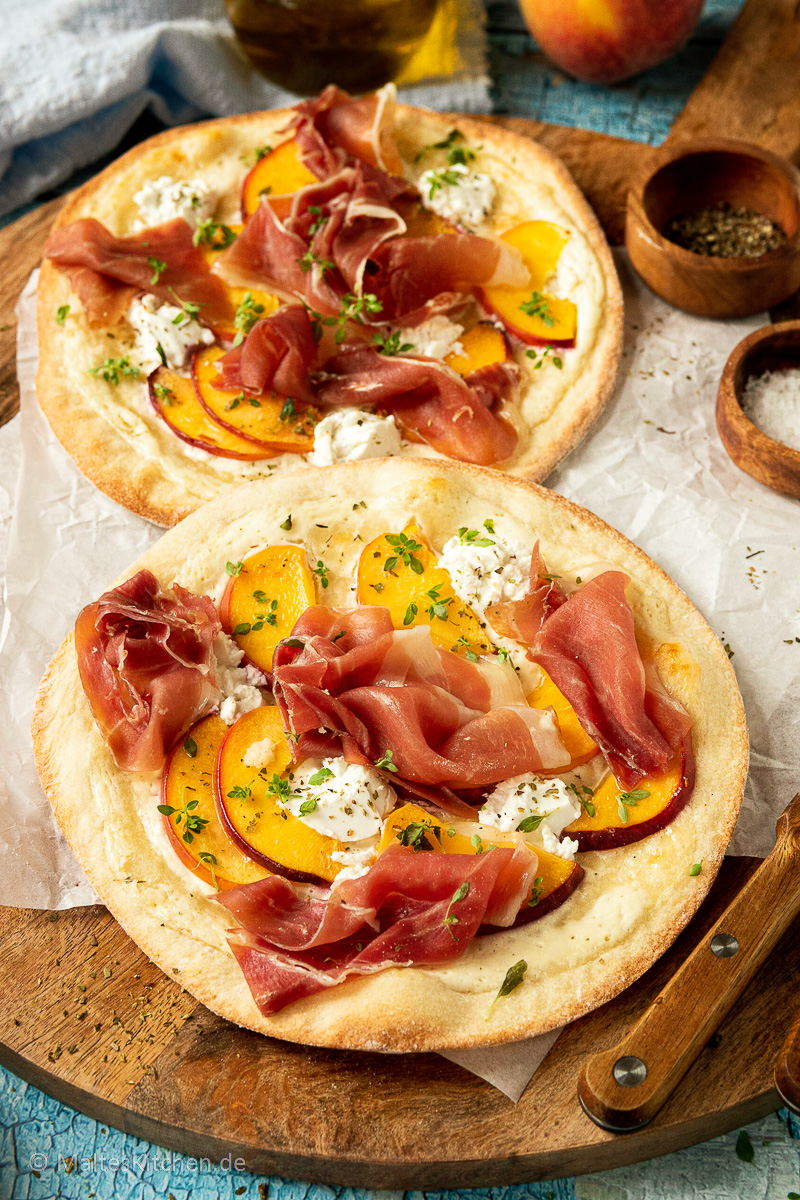 Knuspriger Flammkuchen mit Pfirsichen, Serrano-Schinken und Ziegenfrischkäse.