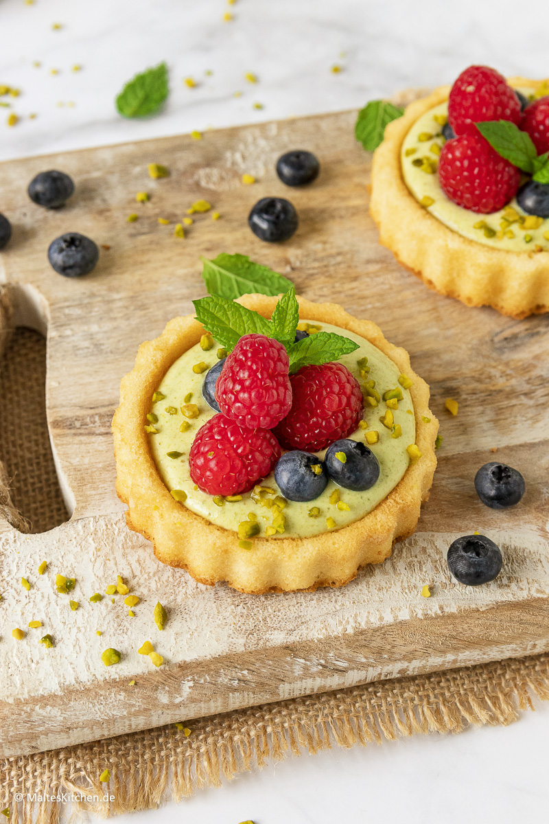 Törtchen mit Biskuitboden, leckerer Pistaziencreme und Himbeeren.