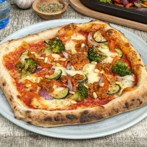 Leckere vegetarische Pizza mit geröstetem Gemüse und Pesto