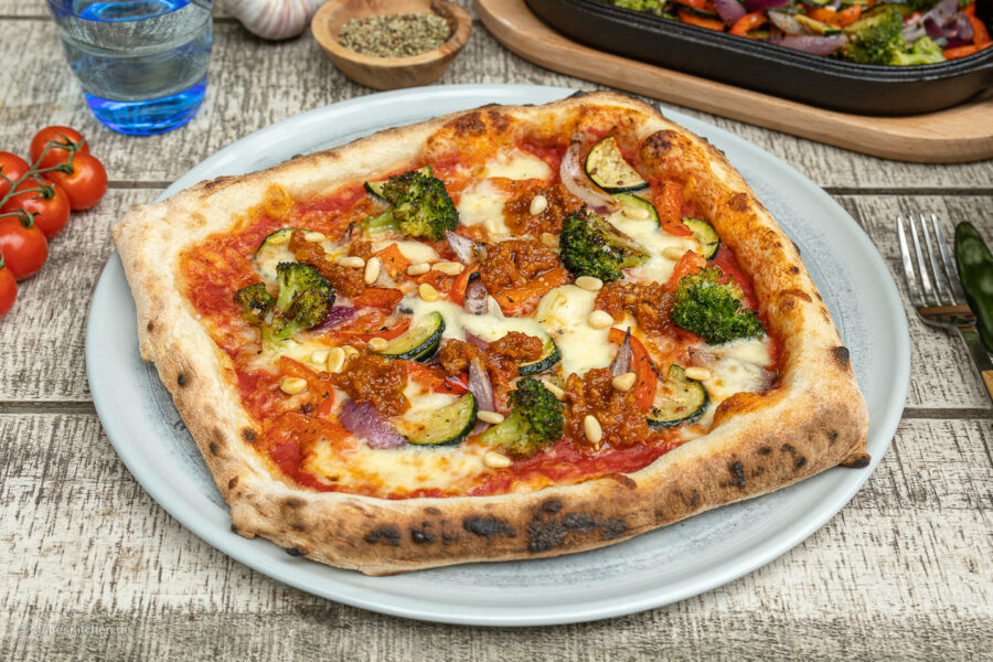 Leckere vegetarische Pizza mit geröstetem Gemüse und Pesto