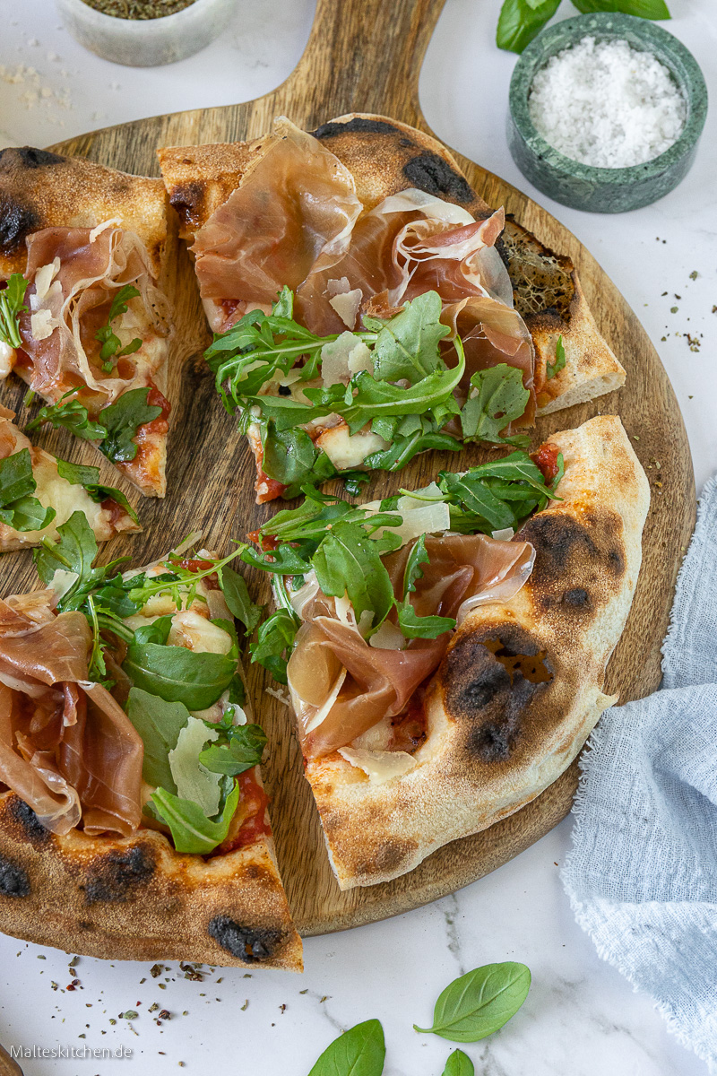 Knusprige Pizza mit Schinken und Rucola.