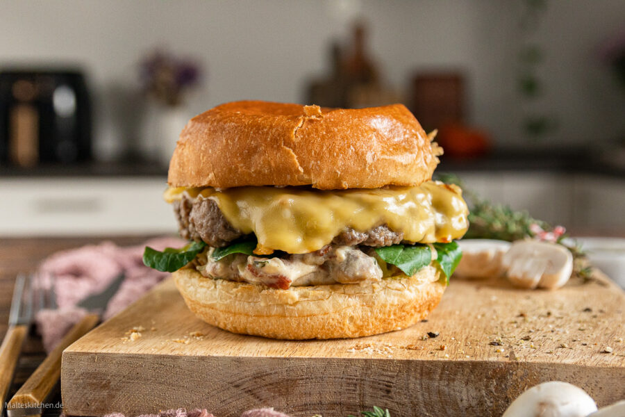 Burger mit Champignons in Pilzrahmsauce, geschmorten Zwiebeln und Bergkäse