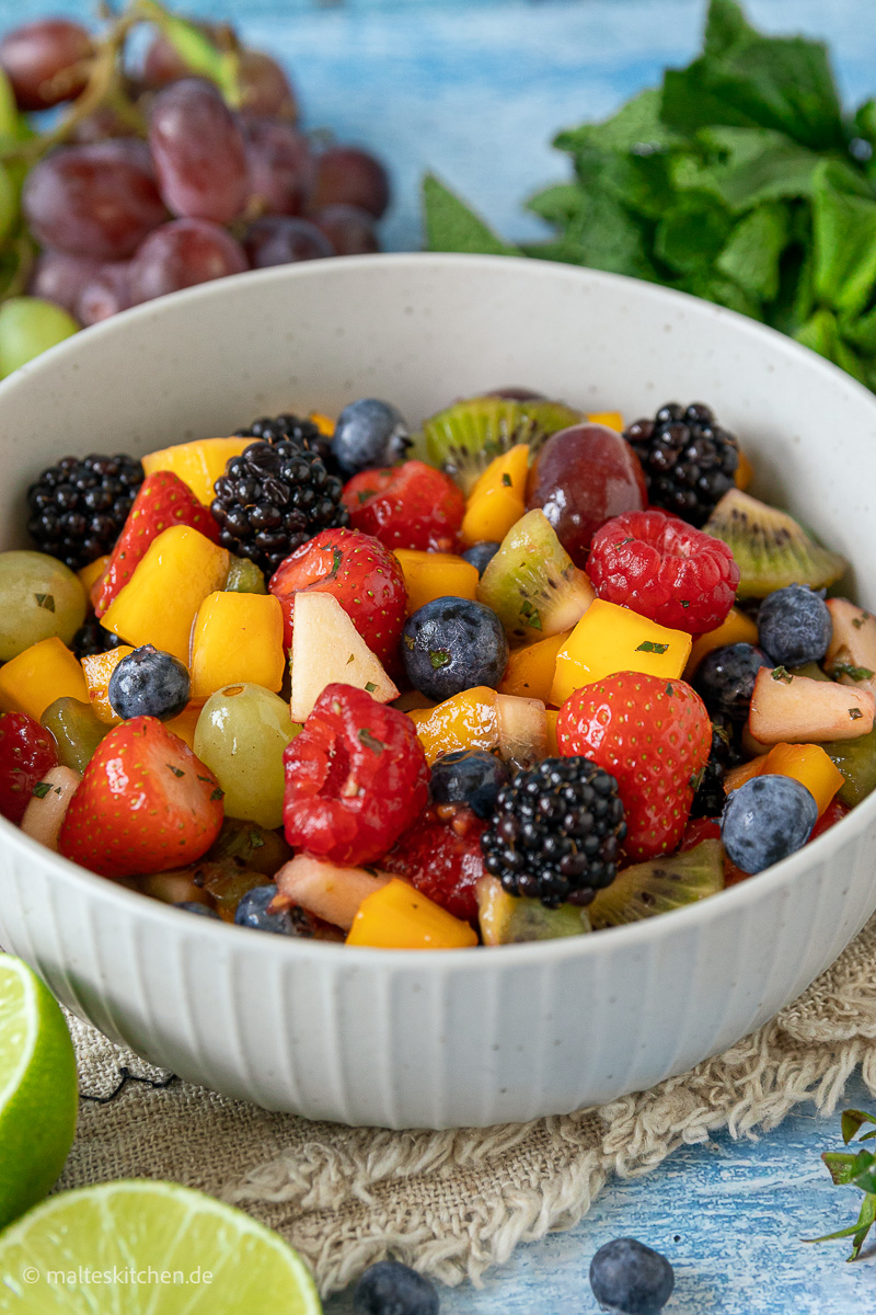 Obstsalat mit Mango, Beeren und Honig.