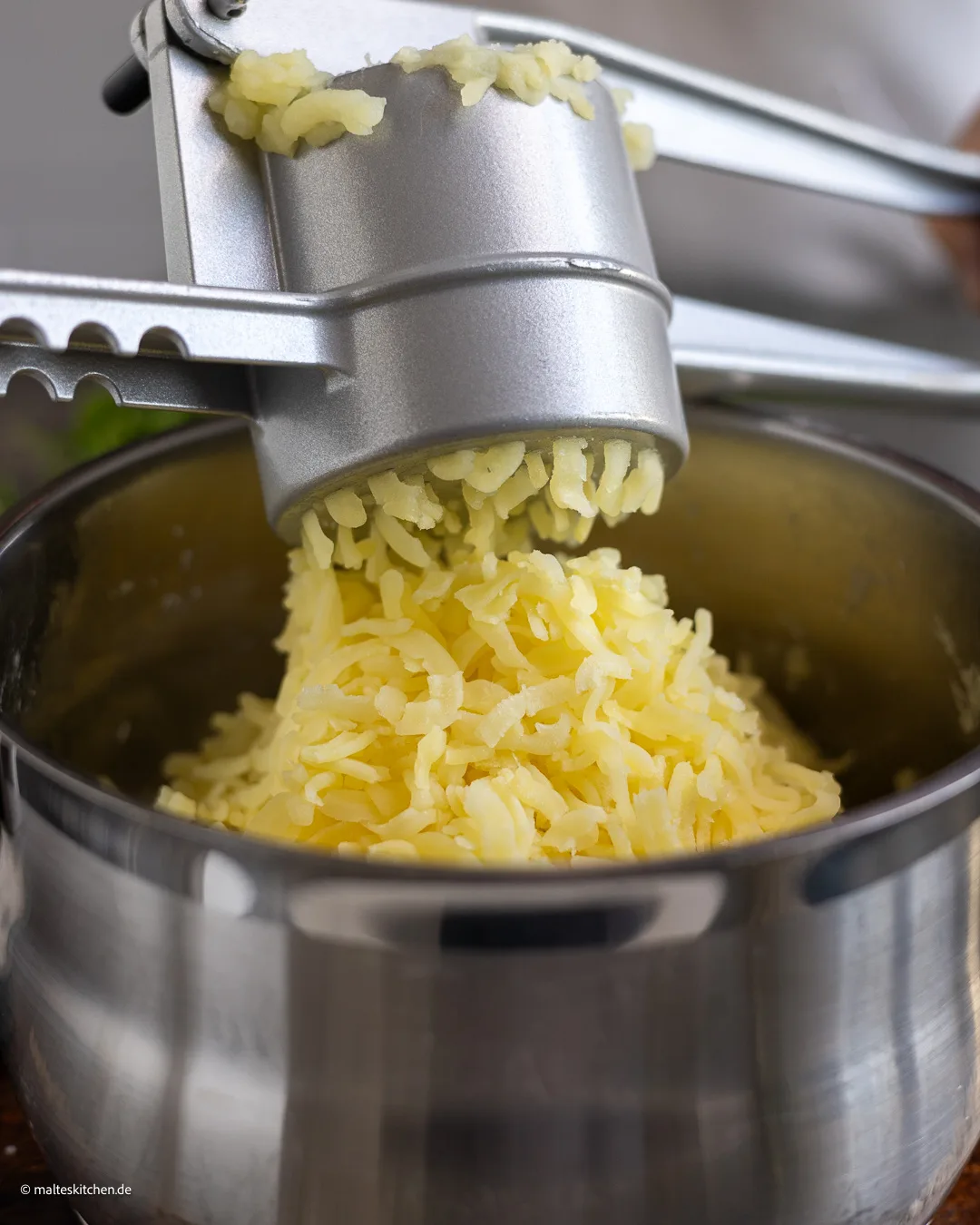 Kartoffeln durch die Kartoffelpresse drücken